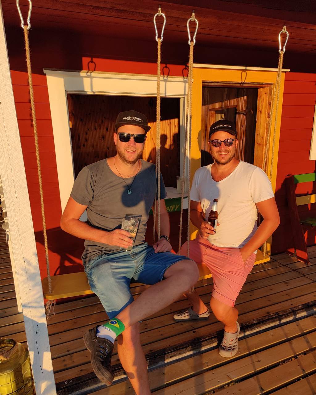 Jannis Pohl (a sinistra) e Timo Pohl (a destra) sul dondolo della veranda di una casa di tronchi, al tramonto